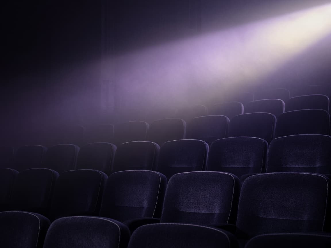 Empty cinema seats crossed by a beam of violet light